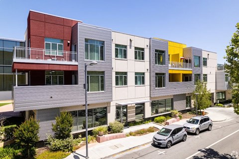 a row of apartment buildings with cars parked in front of them