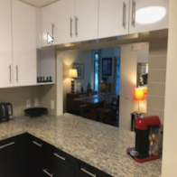 a kitchen with a counter top looking into a living room