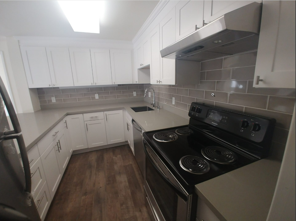 an empty kitchen with white cabinets and black appliances