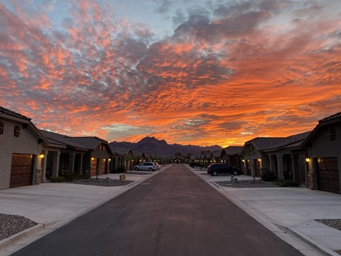 A street in a residential area with houses on both sides and a mountain in the distance.