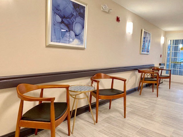 a room with chairs and a table and a painting on the wall