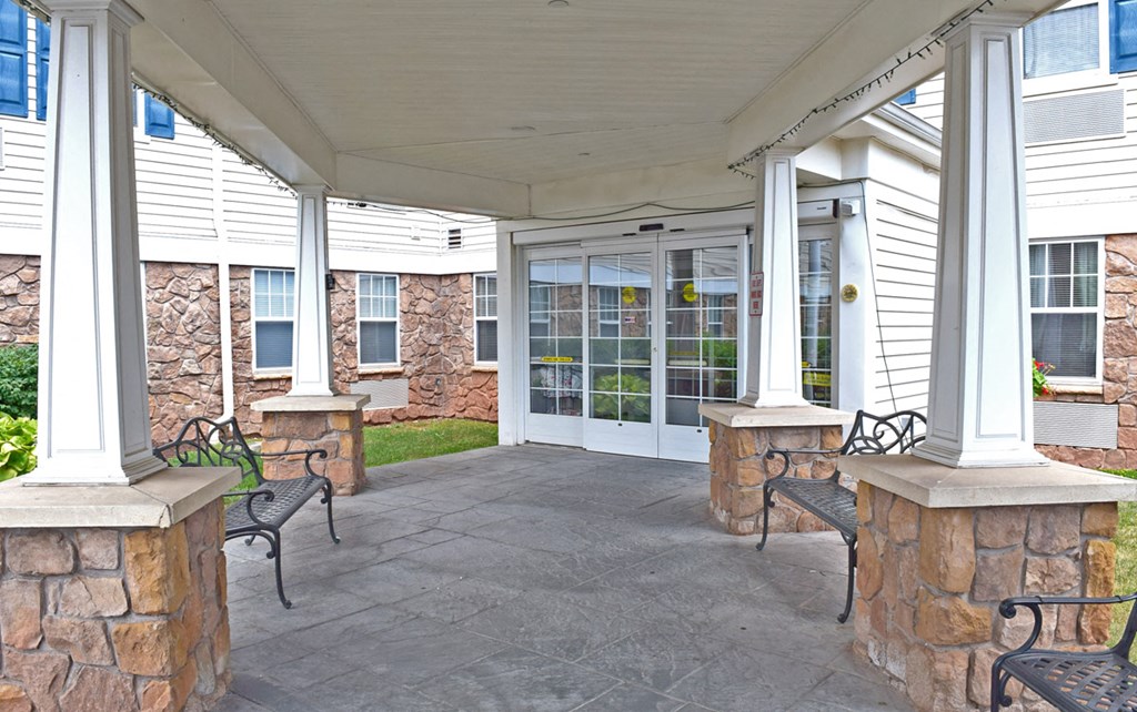 the front porch of a home with benches and columns