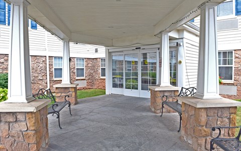 the front porch of a home with benches and columns