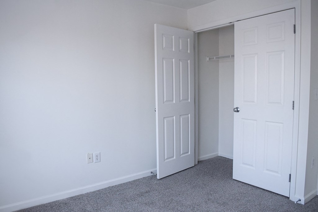 an empty room with a white door and a closet