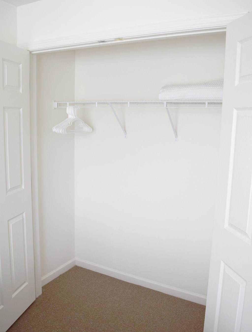 a small closet with white shelves and a white closet door