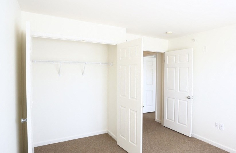 an empty bedroom with white doors and a closet