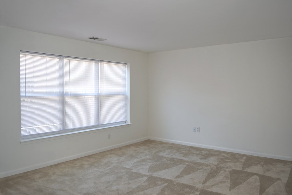 an empty room with a window and white walls