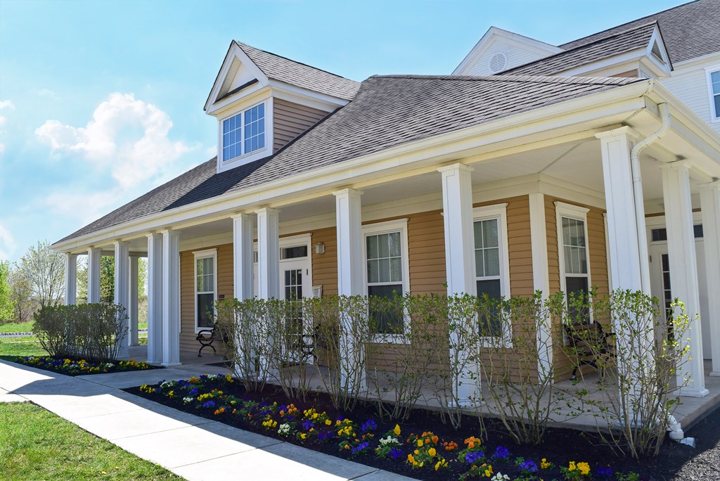 the front porch of a home with flowers and a walkway