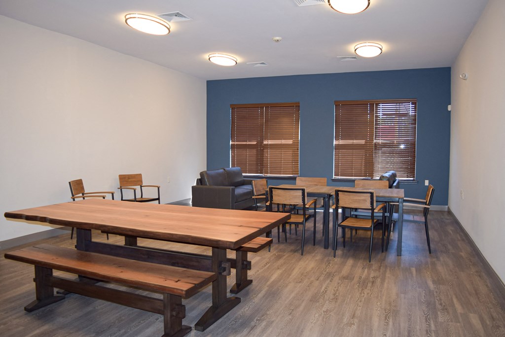 a common room with tables and chairs and a blue wall and windows