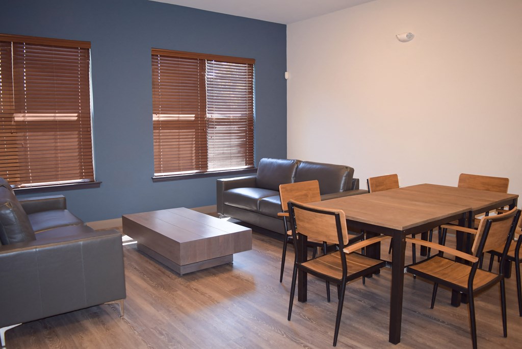 a living room and dining room with a wooden table and leather furniture