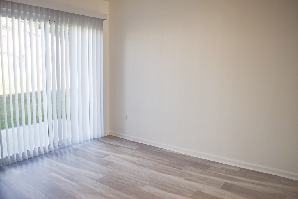 an empty living room with a large window and wooden floors