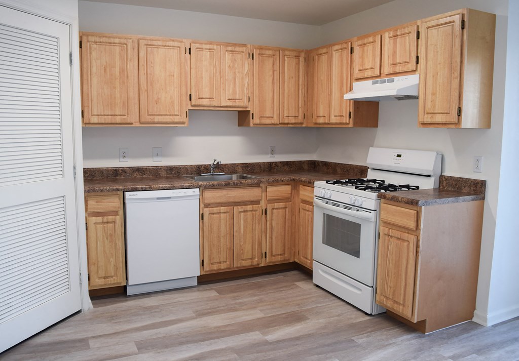 an empty kitchen with wooden cabinets and white appliances