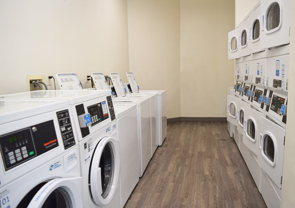 a row of washers and dryers in a laundry room with many washing machines