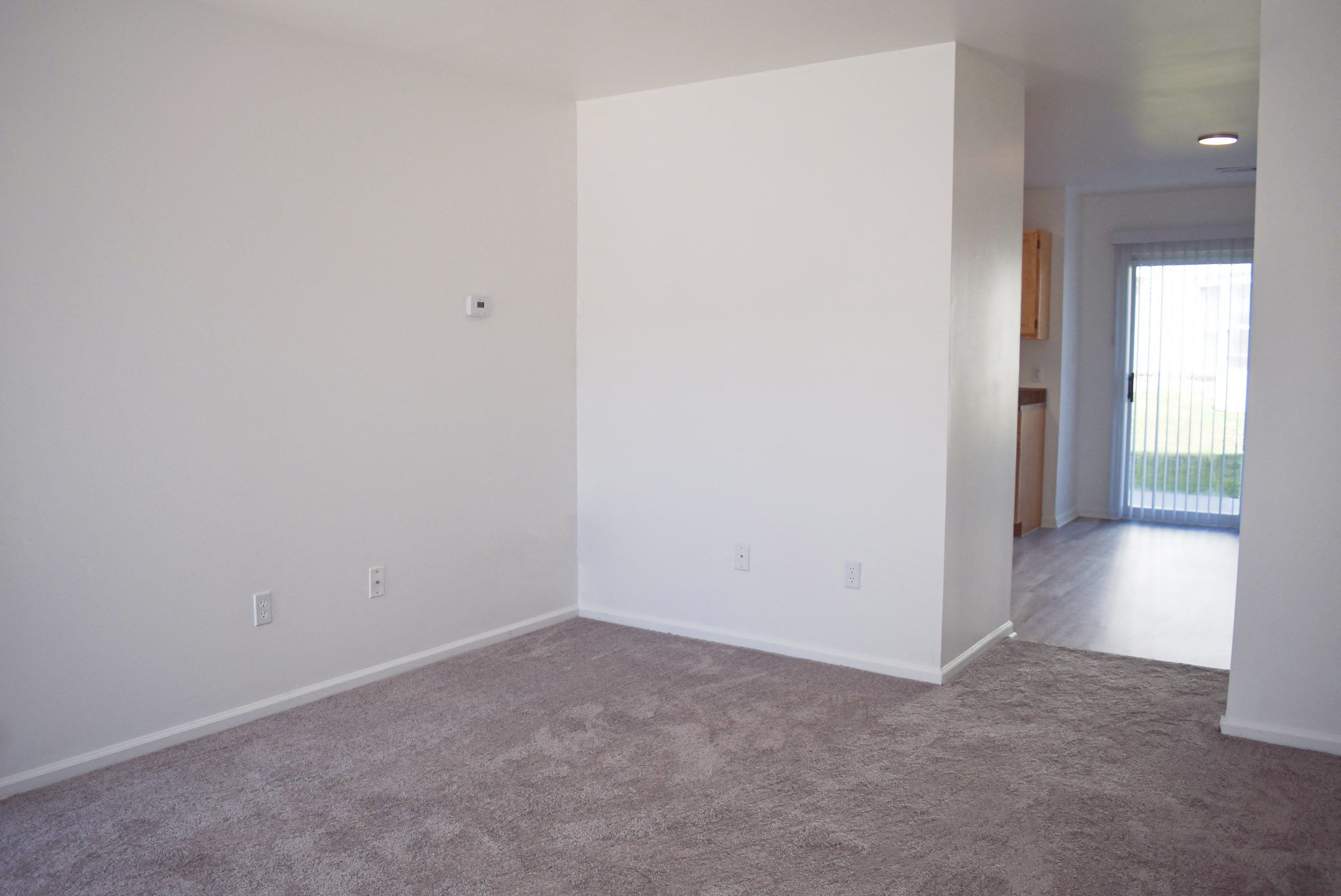 an empty living room with white walls and carpet
