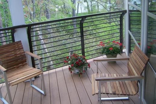 a balcony with two wooden chairs and flowers on it