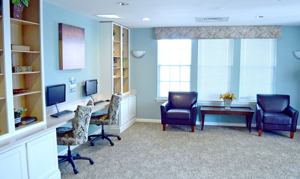 a home office with a desk and chairs and a window