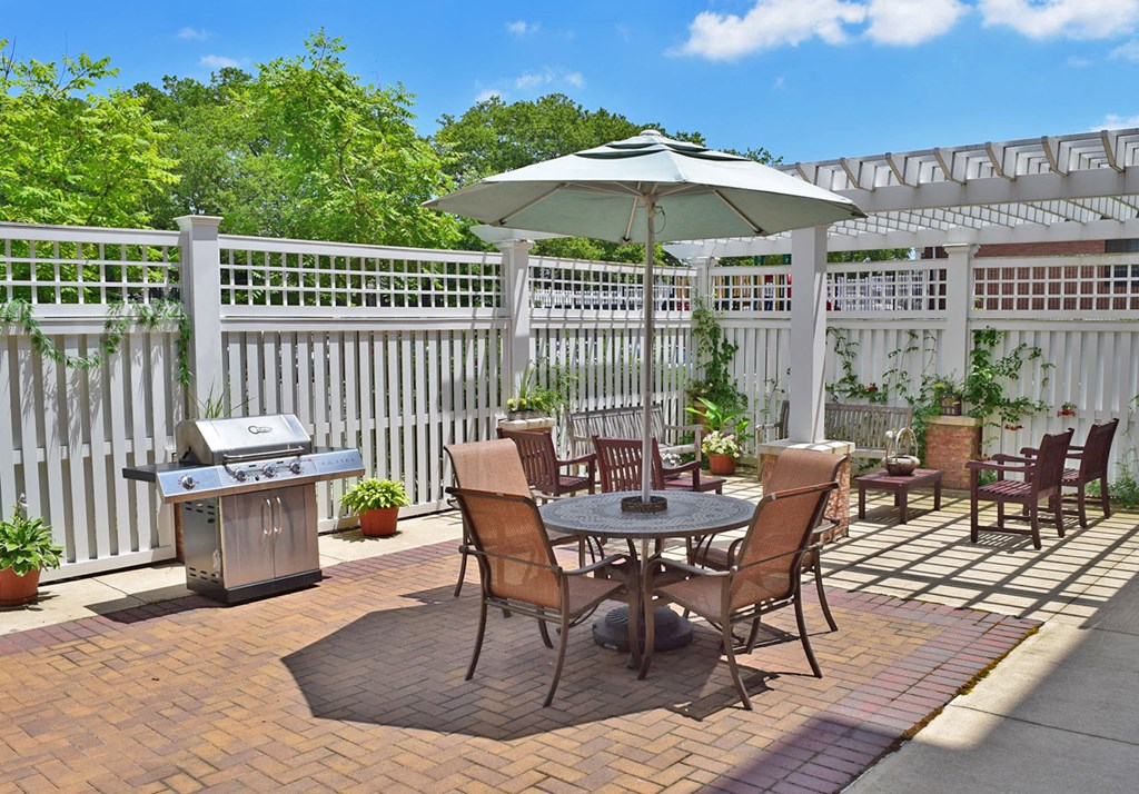 a patio with a table and chairs and a grill
