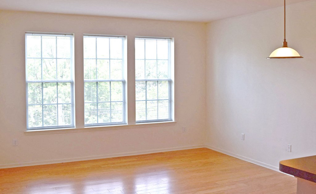 an empty living room with three windows and a lamp