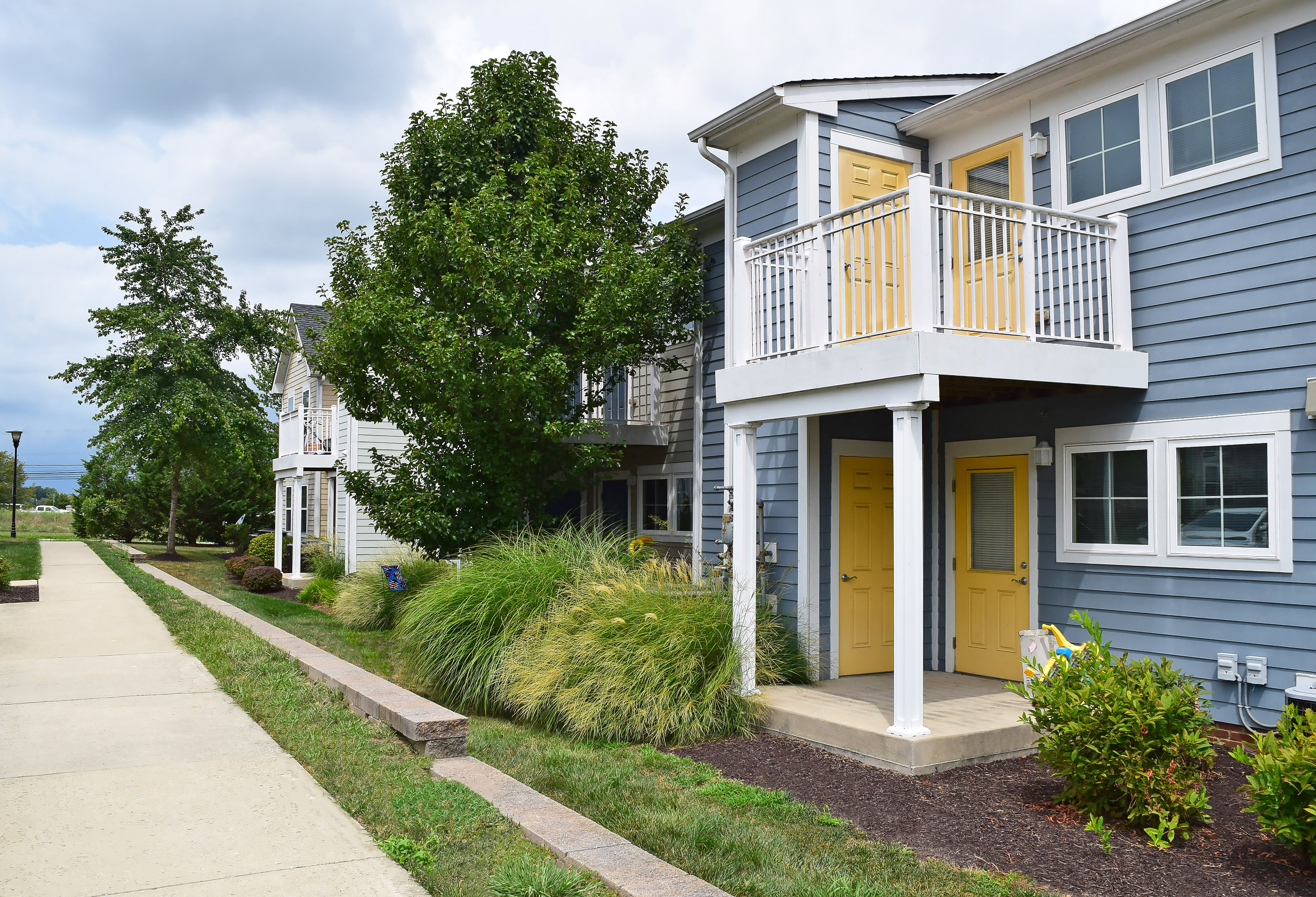 a row of blue houses with a yellow door and a sidewalk