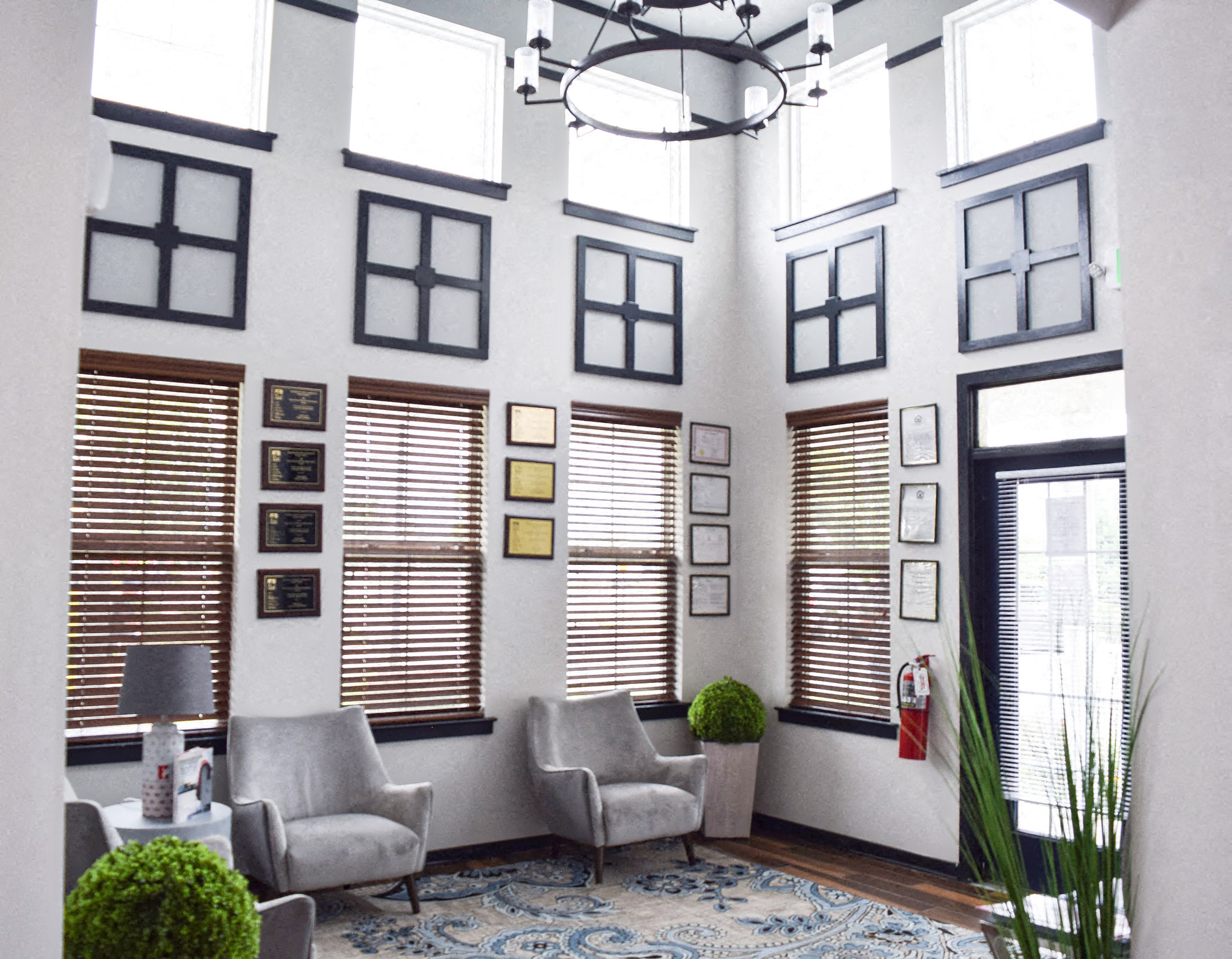 a living room with windows and chairs and a rug