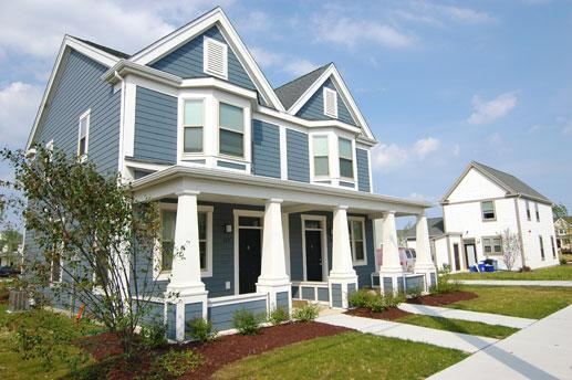 a blue house with white pillars and a sidewalk
