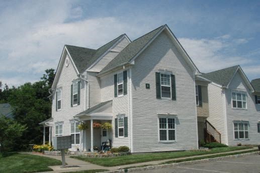 a white house with white siding  and a street