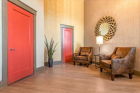 a living room with two chairs and a red door