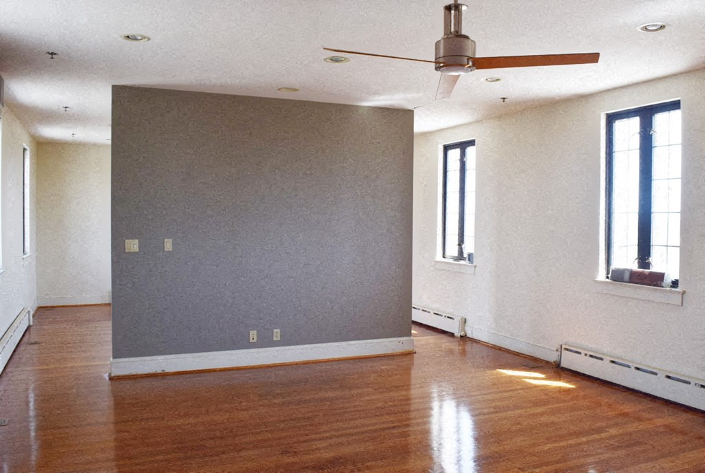an empty living room with wood floors and a ceiling fan