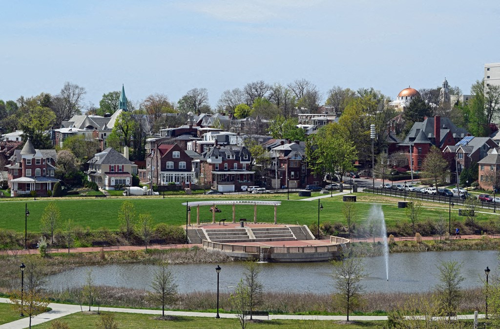 a park with a pond and houses in the background
