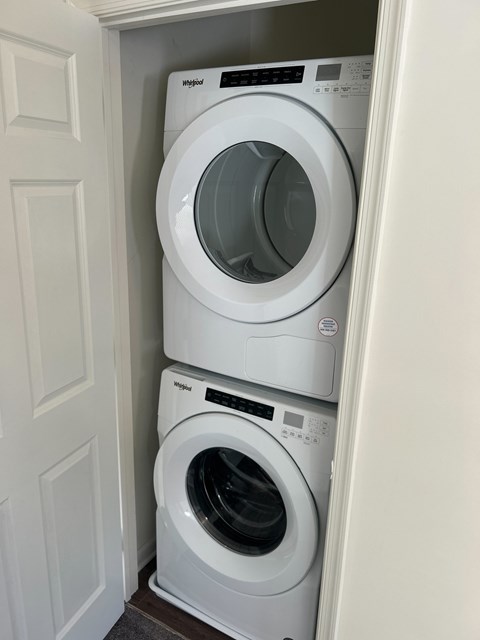 Two white washing machines stacked in a small space.