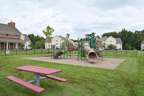 A playground with a red picnic table and a green slide.