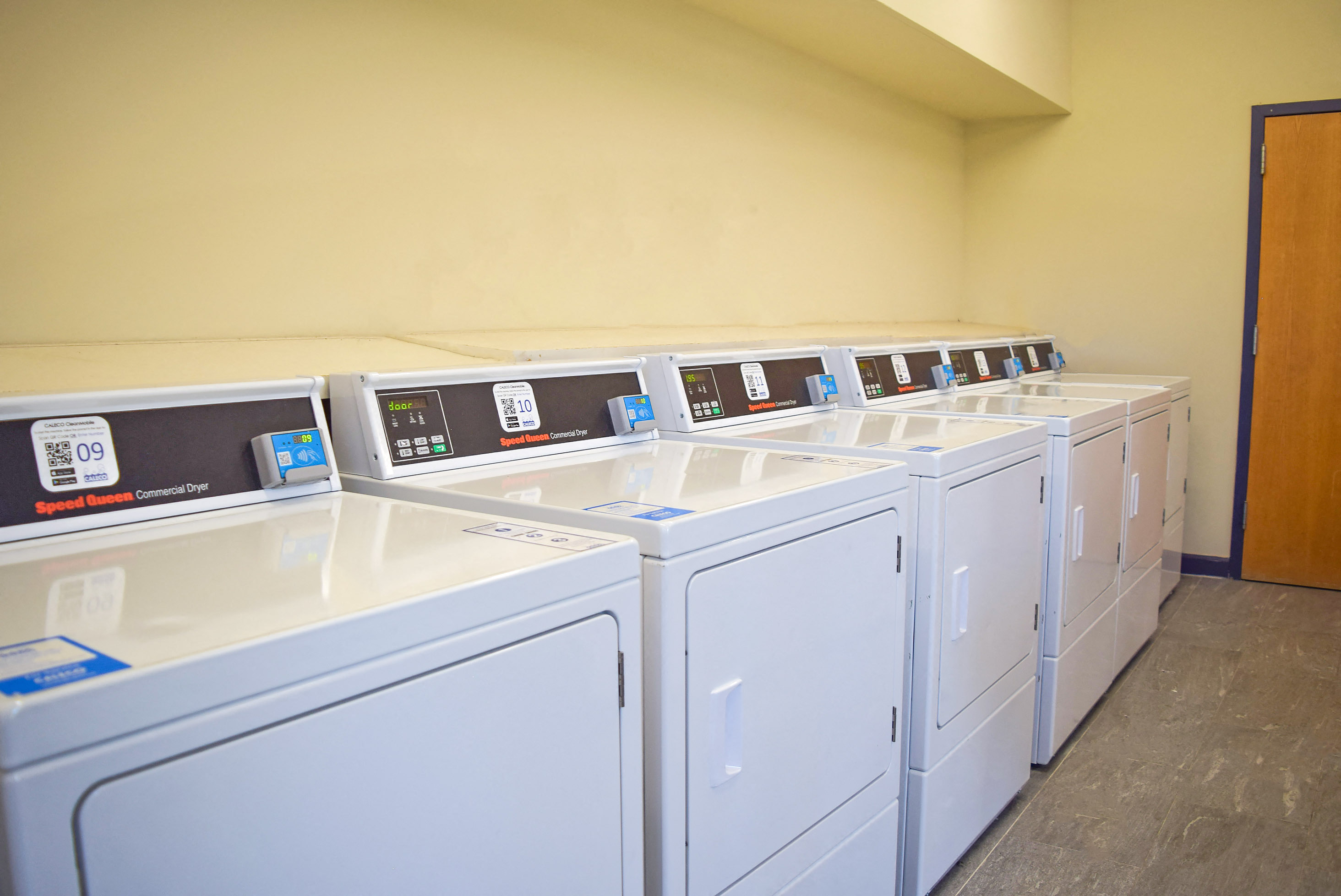 a row of washers and dryers in a laundry room