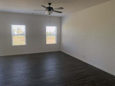 an empty living room with wood floors and a ceiling fan