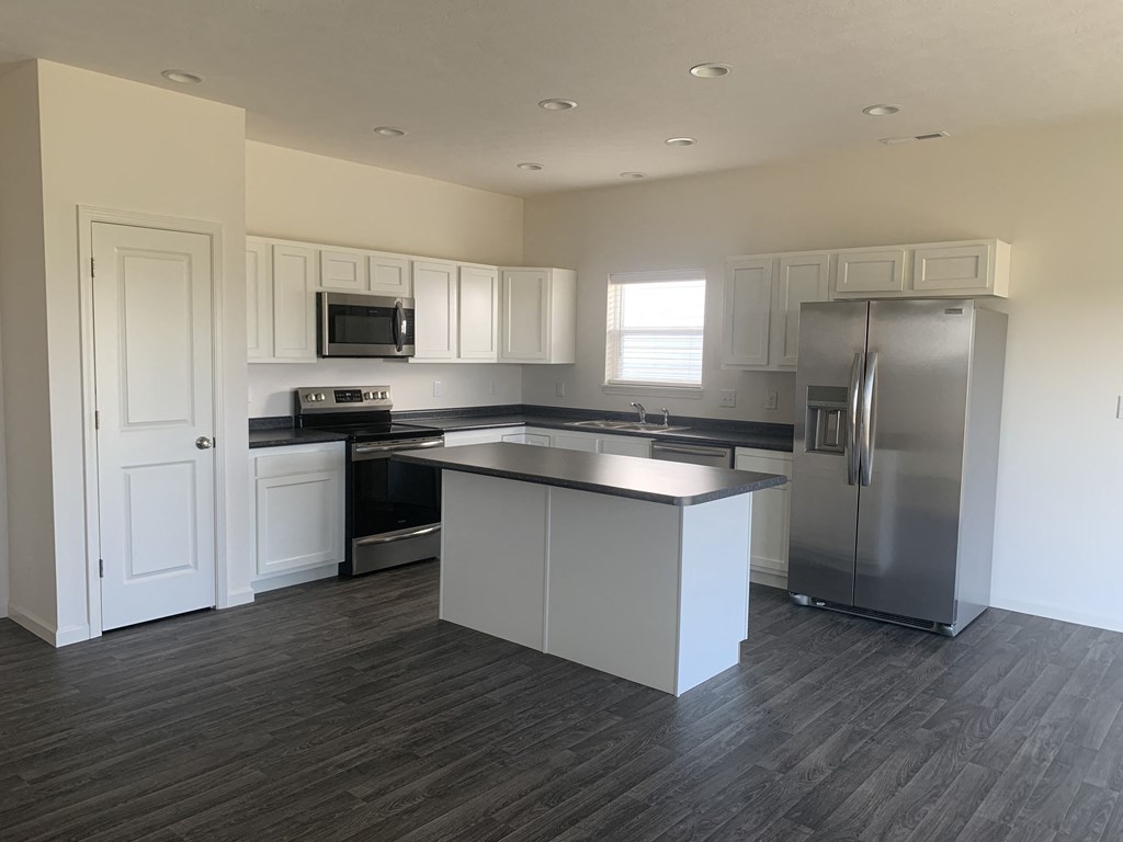 an empty kitchen with stainless steel appliances and white cabinets