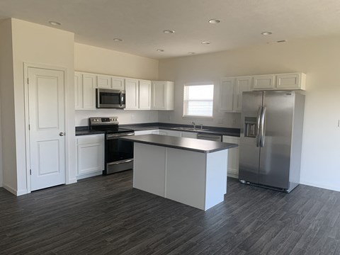 an empty kitchen with stainless steel appliances and white cabinets
