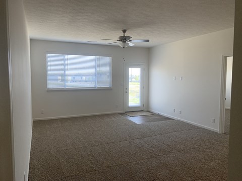 an empty living room with a ceiling fan and a window
