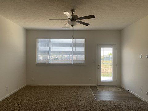 an empty living room with a ceiling fan and a window