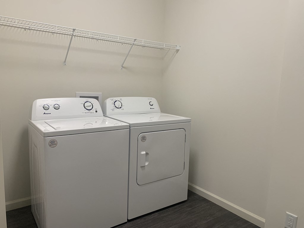 a washer and dryer in a room with a shelf on the wall