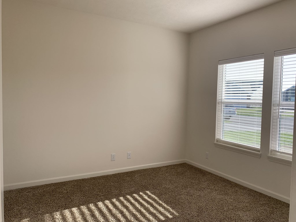 an empty room with two windows and a rug on the floor