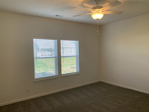 a living room with two windows and a ceiling fan