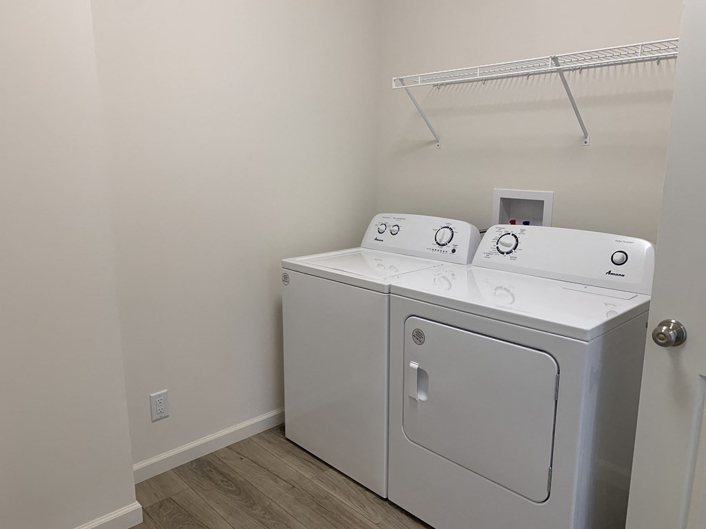 a white washer and dryer in a room with a shelf on the wall
