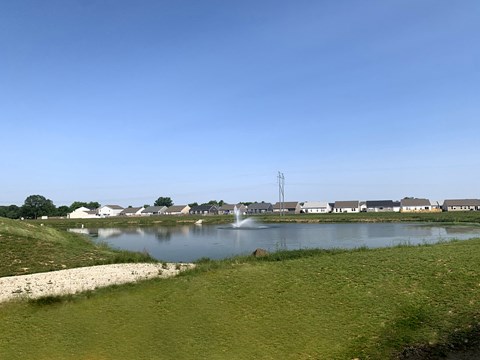 a pond with a fountain in the middle of a field