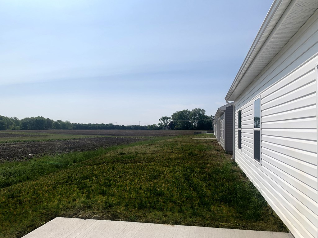 a view of the side of a white building overlooking a field