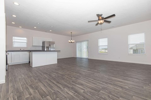 an empty living room and kitchen with a ceiling fan