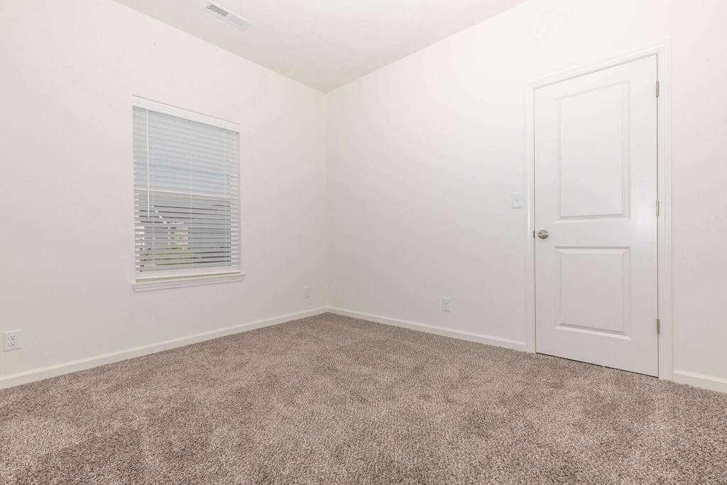 a bedroom with white walls and carpet and a white door