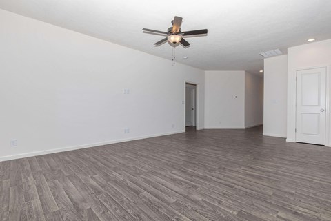 an empty living room with white walls and a ceiling fan
