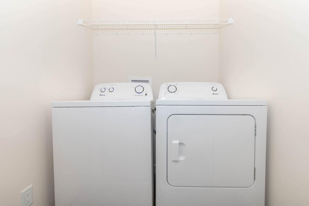 a washer and dryer in a room with a white wall and a shelf
