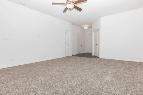 an empty living room with a ceiling fan and white walls