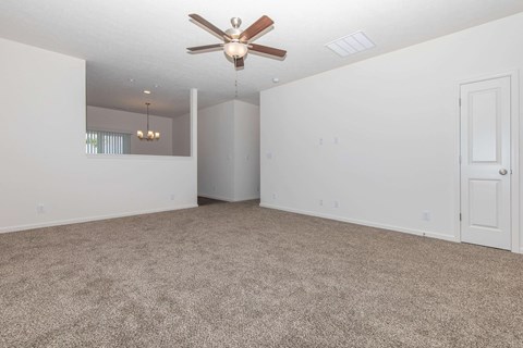 an empty living room with a ceiling fan and white walls