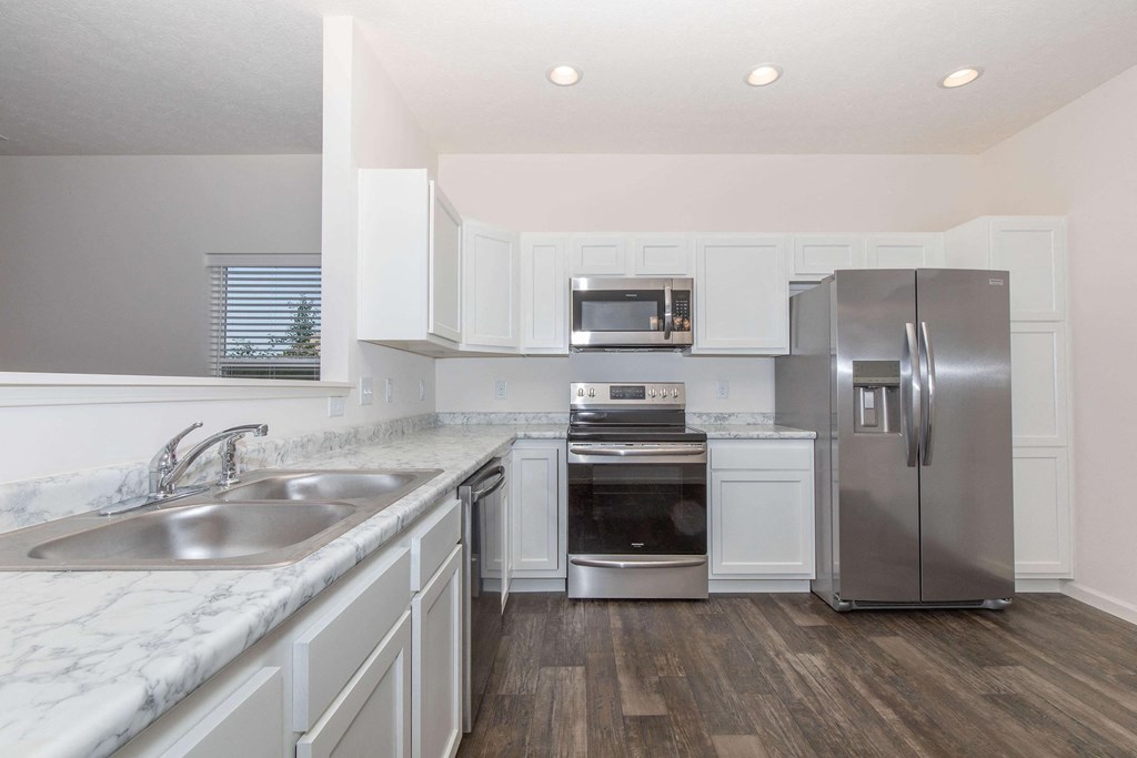 a white kitchen with stainless steel appliances and marble counter tops